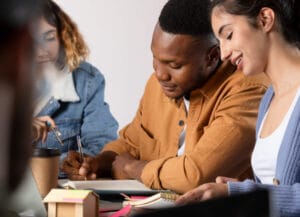 Three learners writing at a shared table