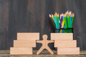 A wooden figure standing between stacked blocks