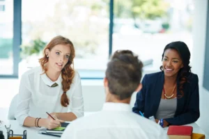 An employment adviser meeting a jobseeker across a desk in an employability provider's office