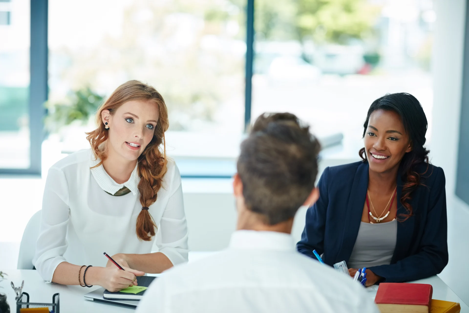 An employment adviser meeting a jobseeker across a desk in an employability provider's office