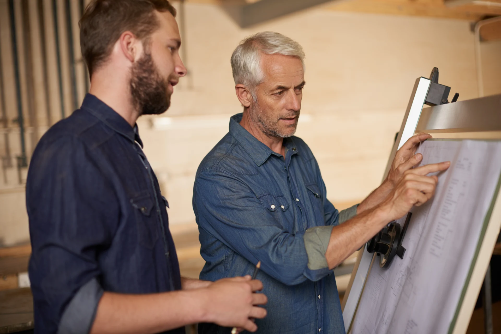 An assessor observing an adult apprentice completing a practical task in a workshop