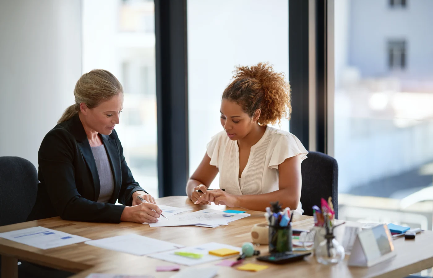 A quality manager giving feedback to an assessor over assessment portfolios in an office