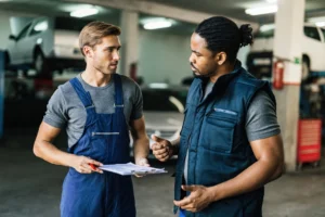 An apprenticeship trainer coaching an adult apprentice at a workbench in a training workshop