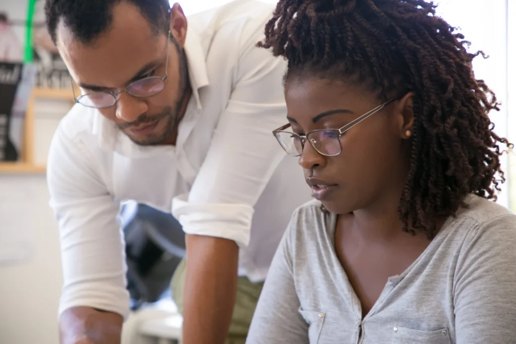 An adult skills coach in a one-to-one progress review with an apprentice in an office