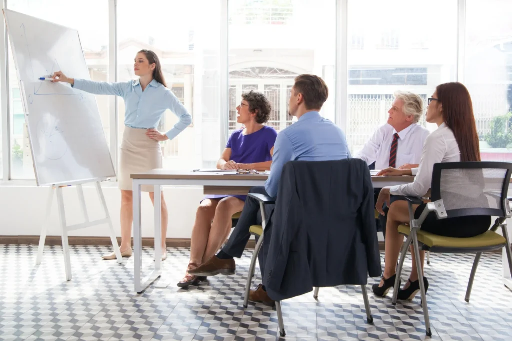 A curriculum manager leading a planning meeting with teaching staff in a college office