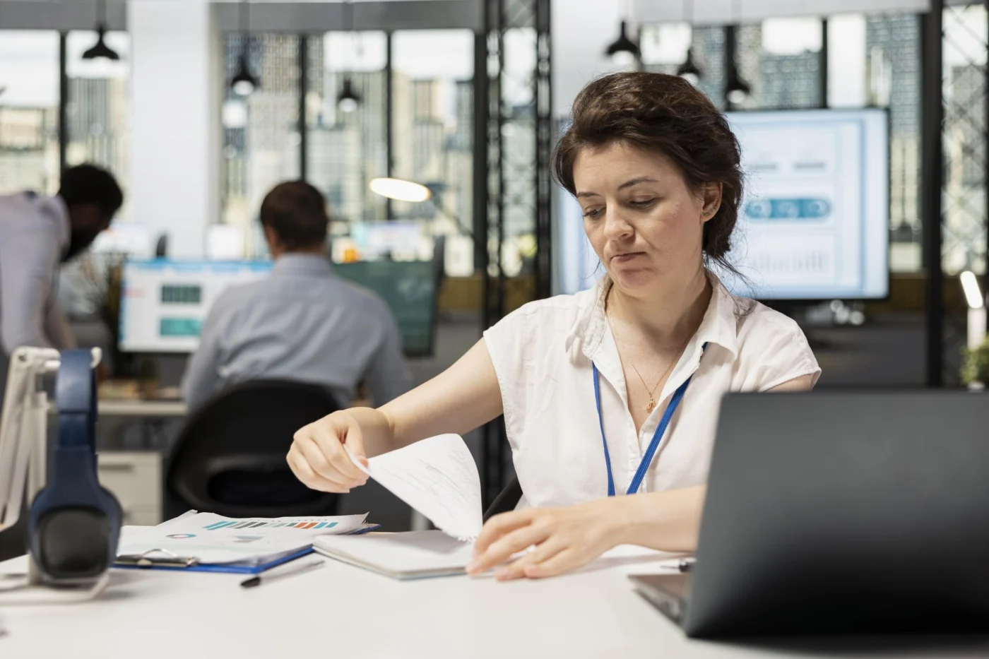 Employee reviewing detailed documents at a desk during a busy workday