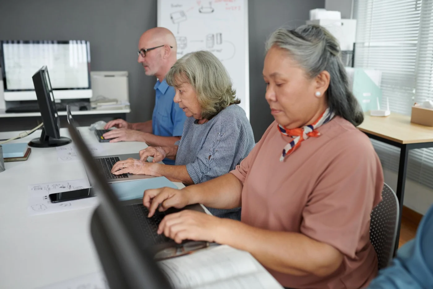 Mature adults working together in a computer skills training class