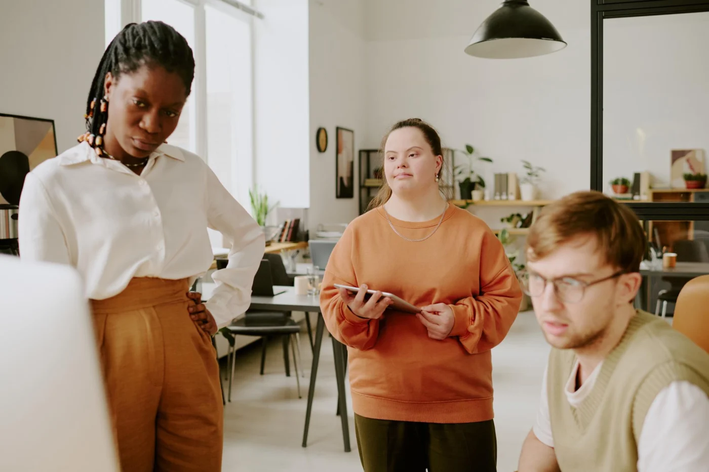 Colleagues, including a team member with Down syndrome, talking together in a bright office