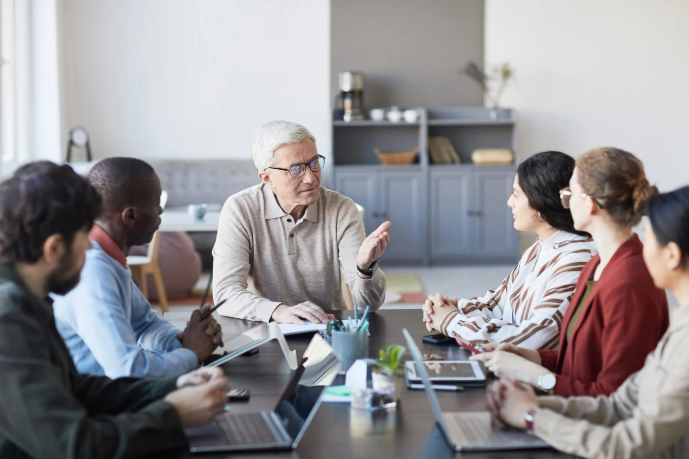 Senior manager leading a team meeting discussion around a table